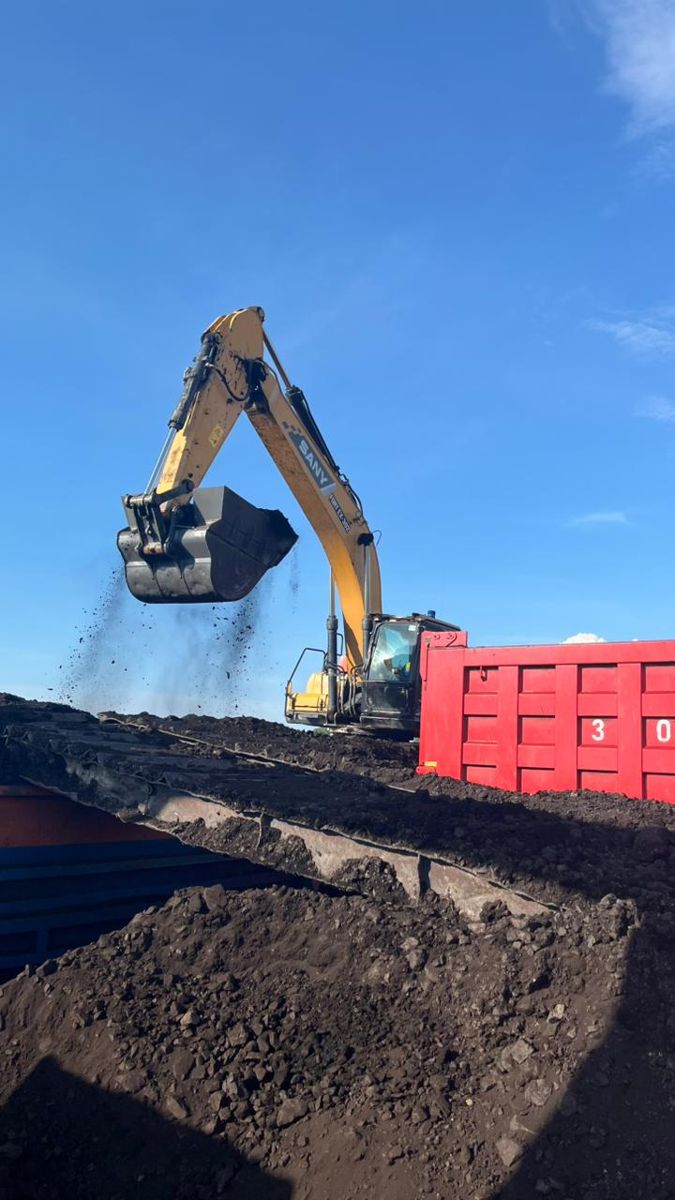 Excavator memuat material ke tongkang